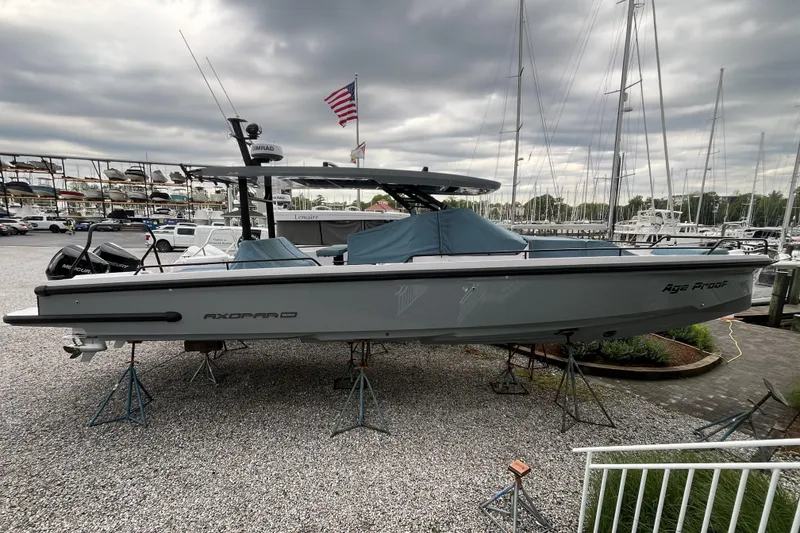 Slide: The Image of 2025 Axopar 37 Sun-Top boat on stands in a marina, under cloudy skies. - 6