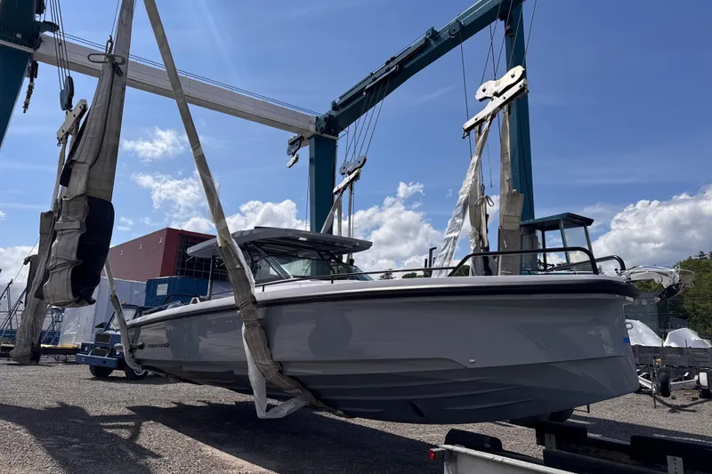 Slide: The Image of 2025 Axopar 37 Sun-Top boat suspended in a marina lift under a clear blue sky. - 62
