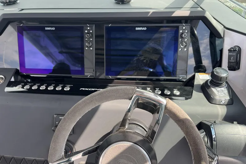 Slide: The Image of 2025 Axopar 37 Sun-Top dashboard with dual Simrad displays and steering wheel. - 63
