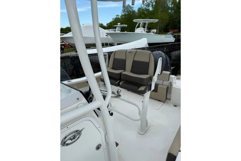 Slide: The Image of 2023 Tidewater 220 CC Adventure boat interior with seating and console, docked outdoors. - 9