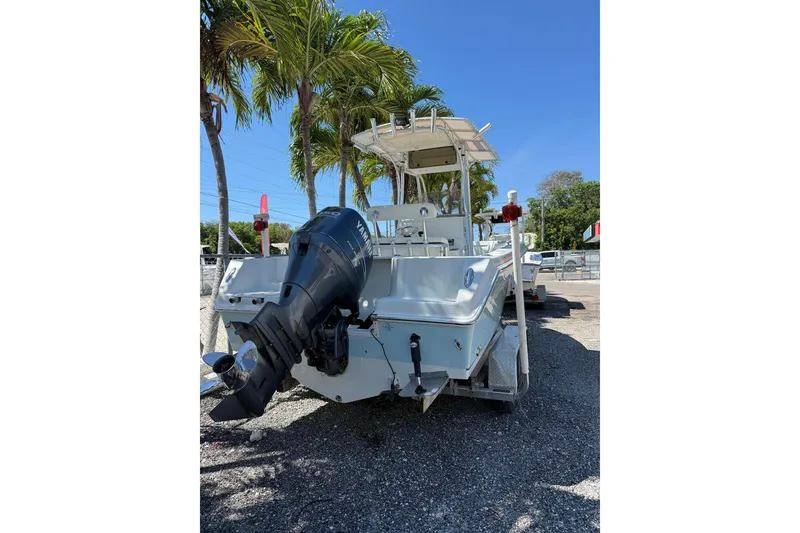 Slide: The Image of 2006 Sailfish 218 CC boat with Yamaha outboard motor, parked under palm trees. - 1