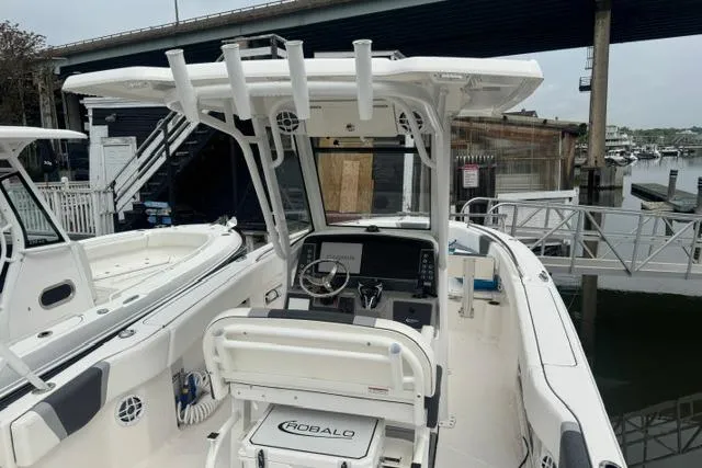 Slide: The Image of 2025 Robalo R250 Center Console boat docked under a bridge, showcasing helm and seating area. - 3