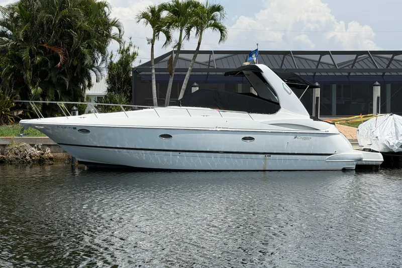 The Image of 2001 Cruisers Yachts 3672 Express docked by palm trees and waterfront home. - 0