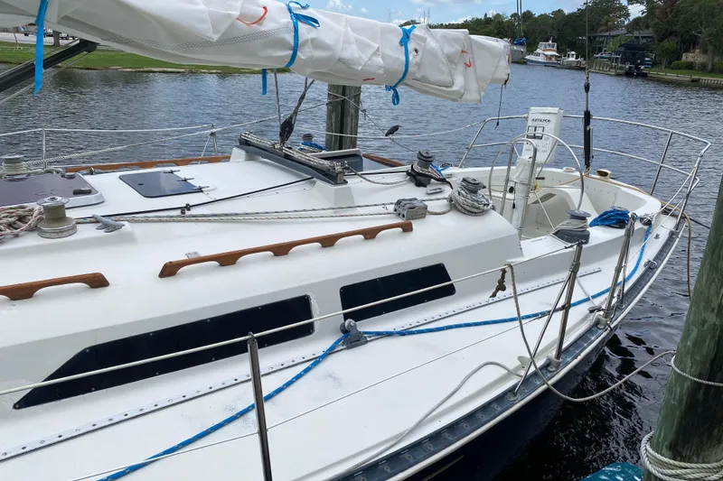 Slide: The Image of 1981 C&C 40 sailboat docked on a calm river, featuring a sleek white deck. - 10