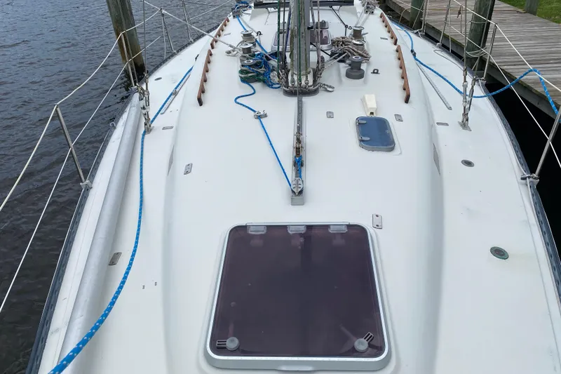 Slide: The Image of 1981 C&C 40 sailboat deck with rigging and hatch, docked by the water. - 11