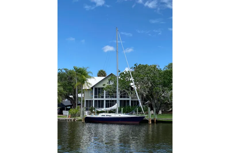Slide: The Image of Sailboat docked by a waterfront house, C&C 40 model, 1981, under a clear blue sky. - 3