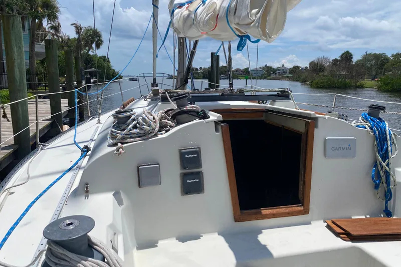 Slide: The Image of 1981 C&C 40 sailboat docked, featuring ropes and equipment on deck under a partly cloudy sky. - 31