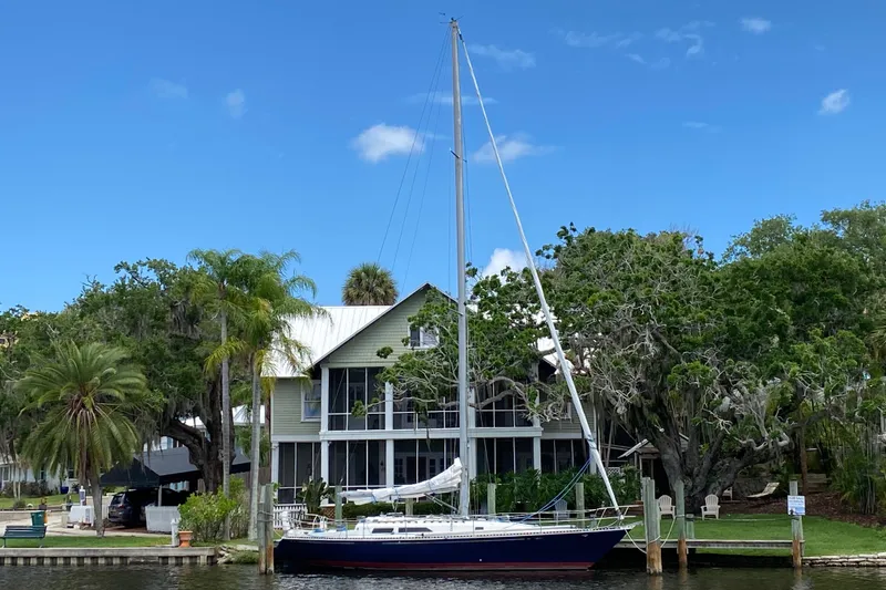 Slide: The Image of 1981 C&C 40 sailboat docked by a house with lush greenery and blue sky. - 38