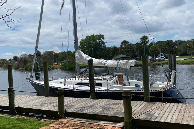Slide: The Image of 1981 C&C 40 sailboat docked by a wooden pier on a calm river. - 4