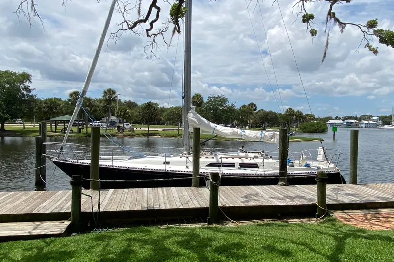 Slide: The Image of 1981 C&C 40 sailboat docked by a scenic waterfront under a cloudy sky. - 5