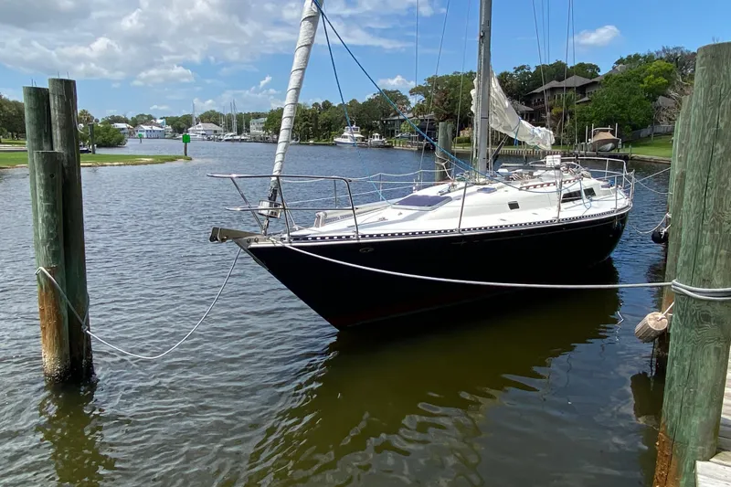 Slide: The Image of 1981 C&C 40 sailboat docked in a serene marina, surrounded by lush greenery. - 7