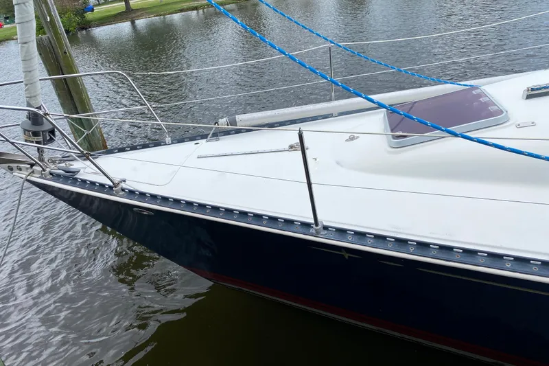 Slide: The Image of 1981 C&C 40 sailboat docked on calm water, featuring sleek white deck and blue hull. - 8