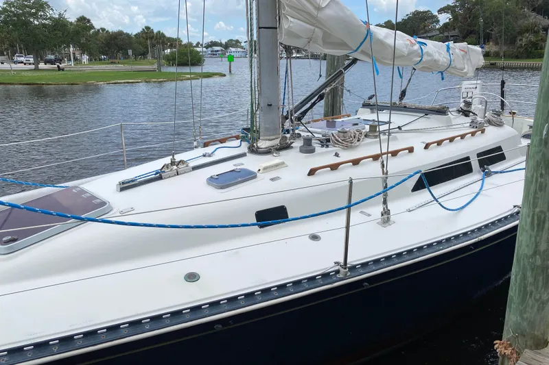 Slide: The Image of 1981 C&C 40 sailboat docked by a calm waterfront, showcasing deck and rigging. - 9