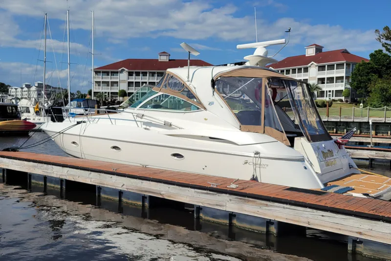 The Image of 2004 Cruisers Yachts 400 Express docked at marina with scenic background. - 0