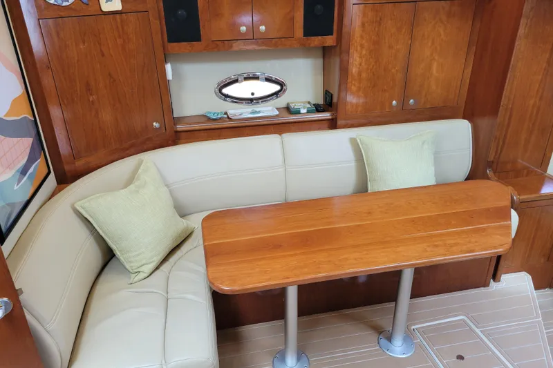 Slide: The Image of Interior of 2004 Cruisers Yachts 400 Express with wooden table and cream seating. - 10