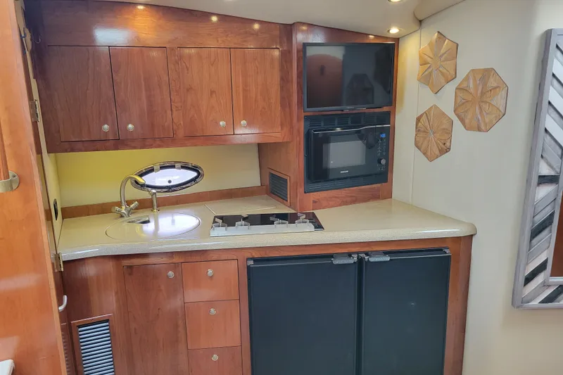 Slide: The Image of 2004 Cruisers Yachts 400 Express kitchen with wood cabinets, sink, stove, and microwave. - 15
