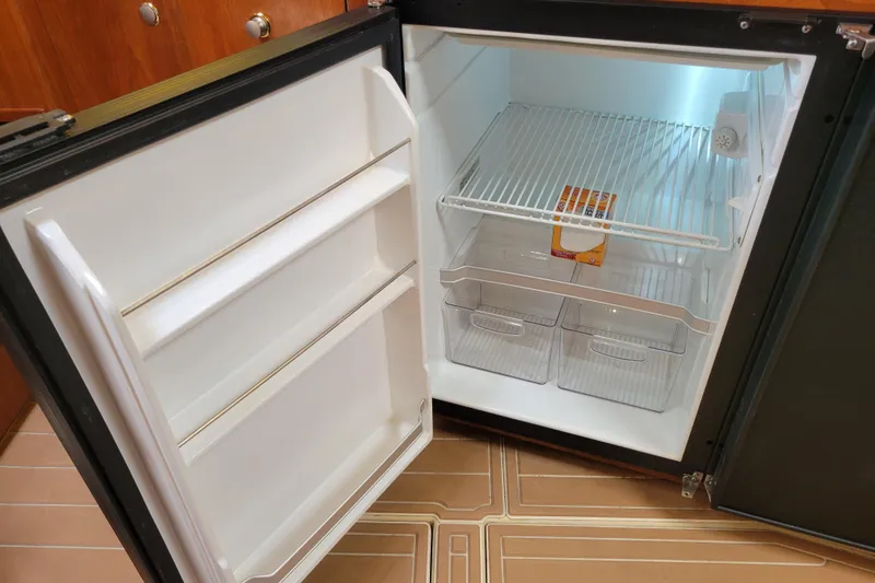 Slide: The Image of Open refrigerator inside 2004 Cruisers Yachts 400 Express, showing empty shelves and drawers. - 17