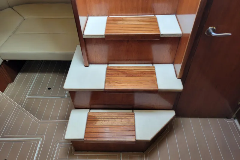Slide: The Image of Interior stairs of a 2004 Cruisers Yachts 400 Express, featuring wooden steps and elegant design. - 23