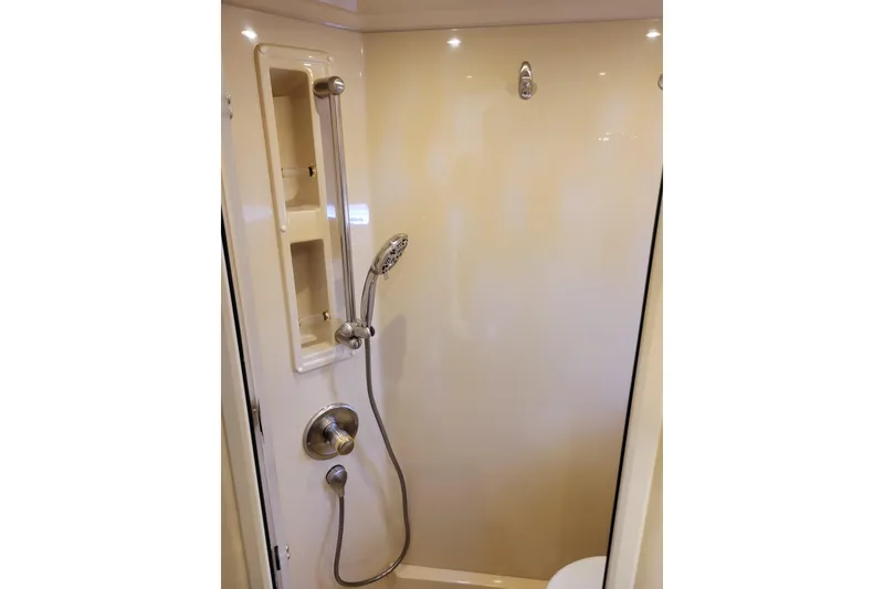 Slide: The Image of Shower area in 2004 Cruisers Yachts 400 Express, featuring handheld showerhead and built-in shelves. - 27