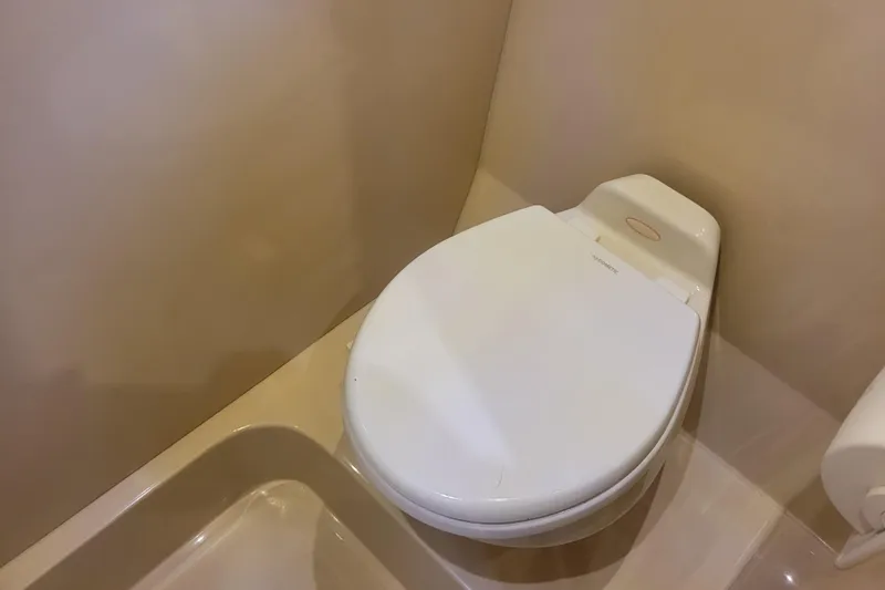 Slide: The Image of Toilet in 2004 Cruisers Yachts 400 Express, featuring a compact, beige marine bathroom design. - 29
