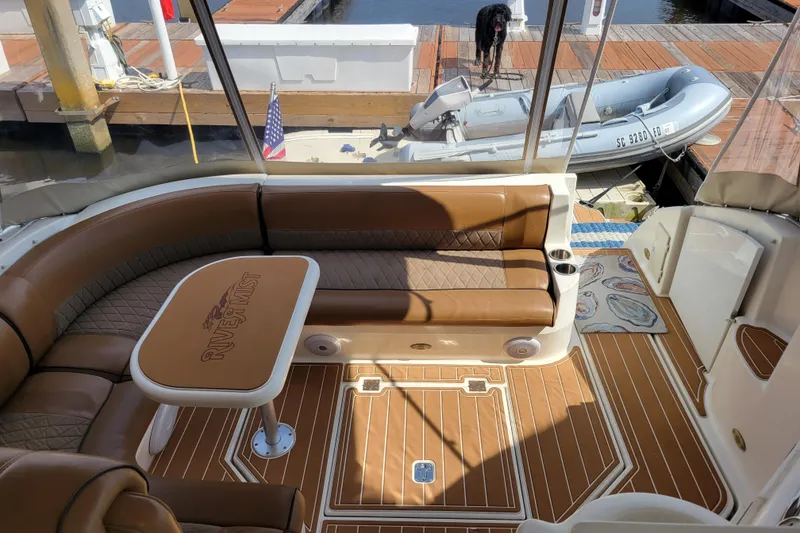 Slide: The Image of Luxurious 2004 Cruisers Yachts 400 Express interior with brown seating and table, docked at marina. - 34