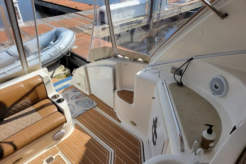 Slide: The Image of 2004 Cruisers Yachts 400 Express interior with brown seating and docked inflatable boat. - 36