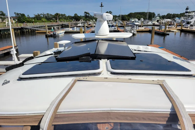 Slide: The Image of 2004 Cruisers Yachts 400 Express docked, featuring solar panels on deck. - 49
