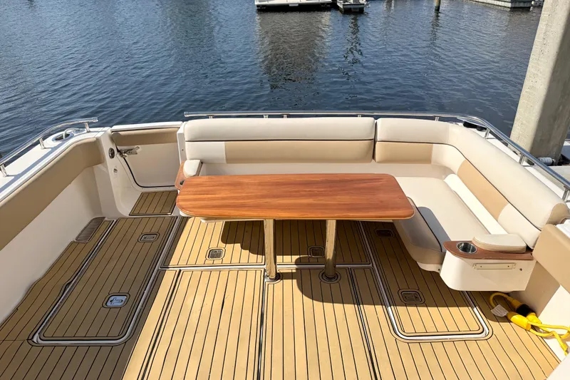 Slide: The Image of 2013 Tiara Yachts 3600 Coronet deck with seating and wooden table, docked by water. - 19