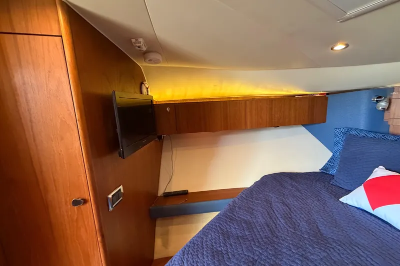 Slide: The Image of 2013 Tiara Yachts 3600 Coronet cabin with wood paneling, TV, and cozy bedding. - 35