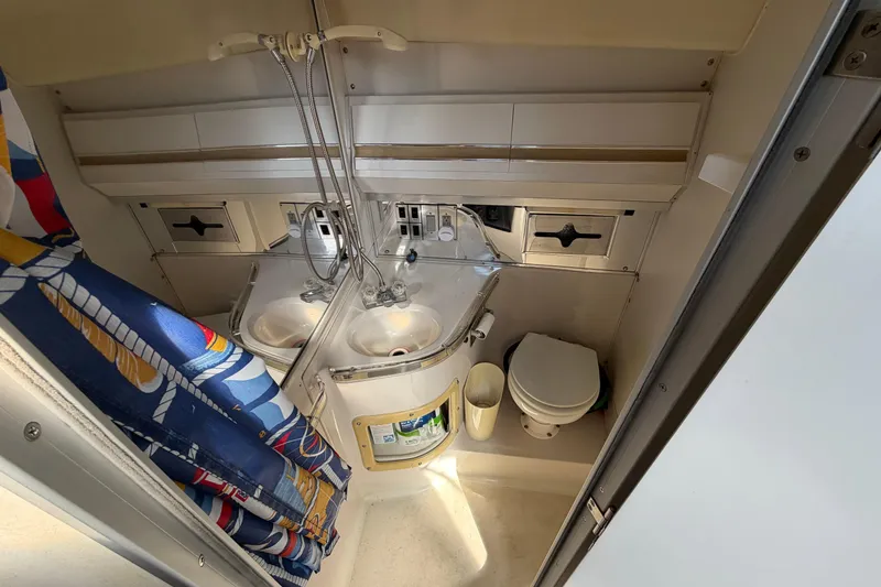 Slide: The Image of 1989 Wellcraft 3400 Gran Sport bathroom with dual sinks, toilet, and colorful shower curtain. - 20