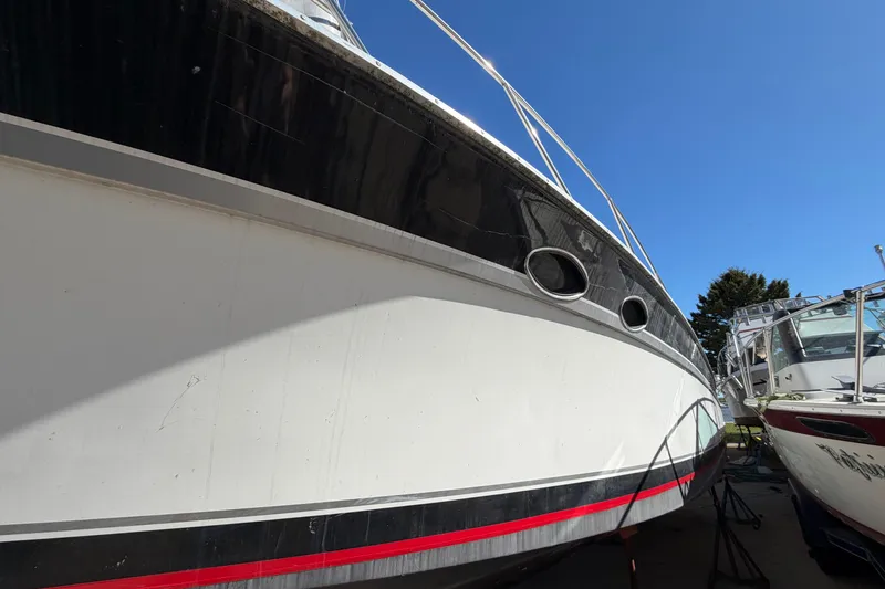 Slide: The Image of 1989 Wellcraft 3400 Gran Sport boat with sleek black and white hull, docked outdoors. - 5
