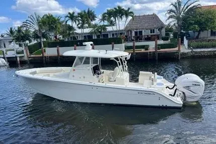 The Image of 2020 Cobia 350 Center Console boat on water, with Yamaha engines, near waterfront homes. - 1