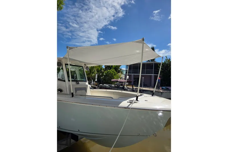 Slide: The Image of 2020 Cobia 350 Center Console boat with canopy, docked under a clear blue sky. - 4