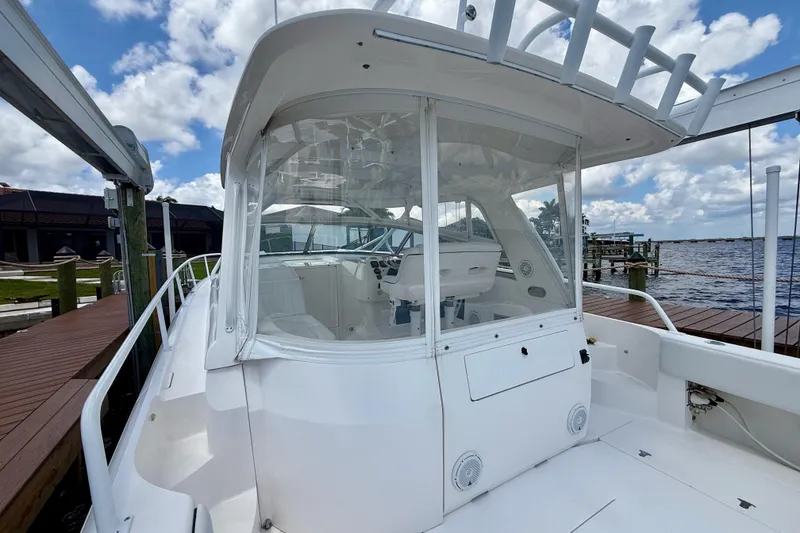 Slide: The Image of 2013 Intrepid 430 Sport Yacht docked, showcasing sleek design and spacious cockpit under a cloudy sky. - 15