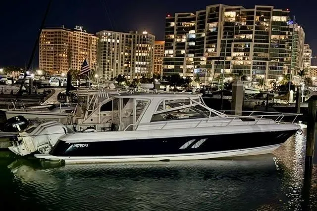 Slide: The Image of 2013 Intrepid 430 Sport Yacht docked at night with city skyline backdrop. - 4