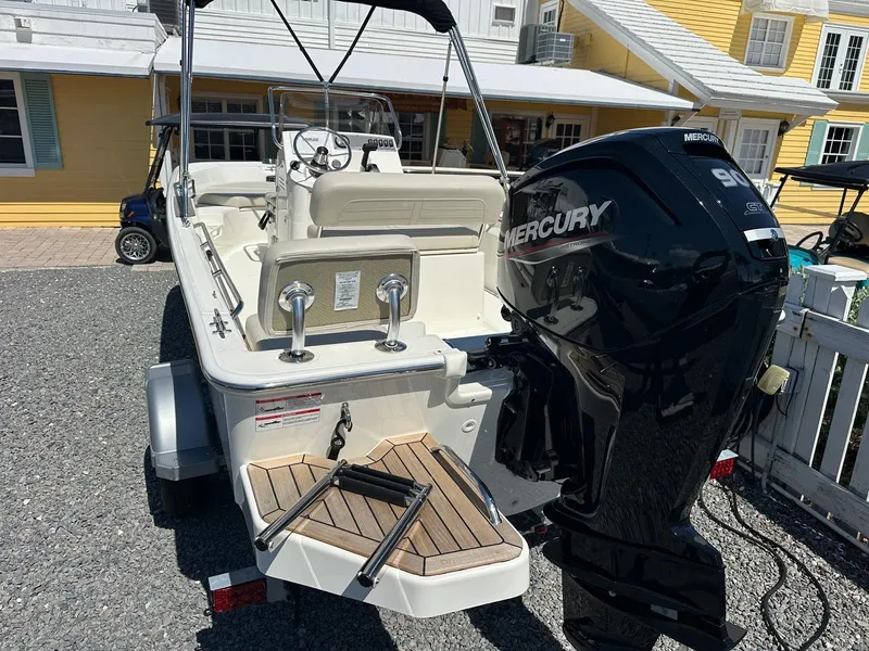 Slide: The Image of Boston Whaler 170 Montauk 2027 with Mercury engine, on a trailer, in front of a yellow building. - 3