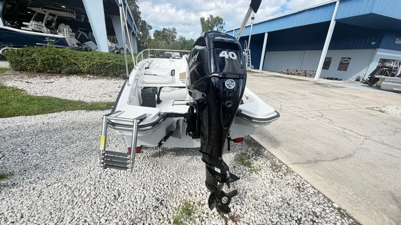 Slide: The Image of A 2027 Boston Whaler 130 Super Sport with a 40 HP engine, parked on a gravel lot. - 6