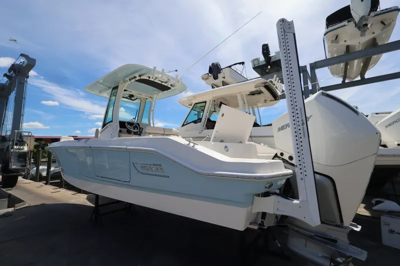 Slide: The Image of A 2027 Boston Whaler 280 Dauntless on a boat lift. It features a blue hull and a hardtop. - 3