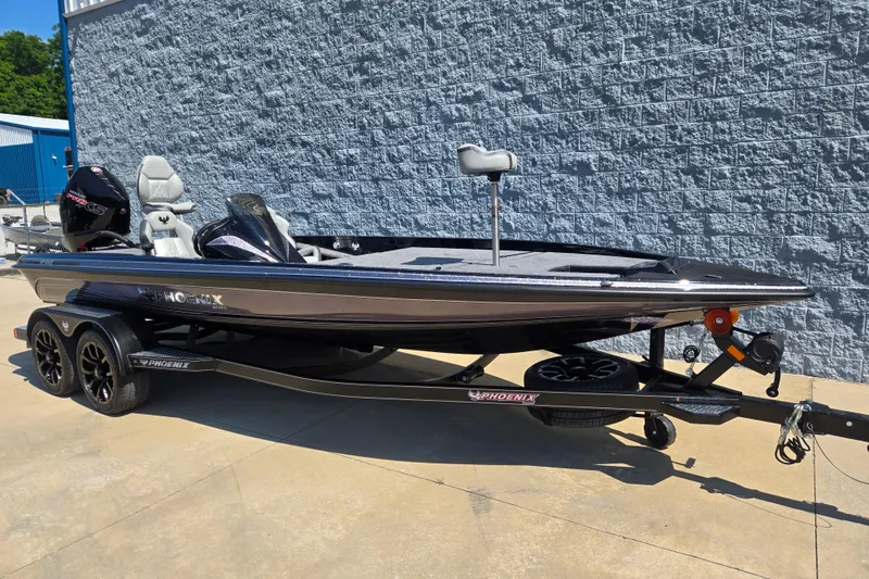 Slide: The Image of 2026 Phoenix 921 Elite X boat on trailer, parked outdoors against a brick wall. - 4