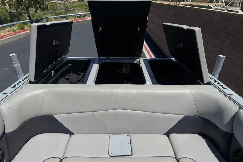 Slide: The Image of 2022 Moomba Max boat interior with open storage compartments and gray seating. - 19