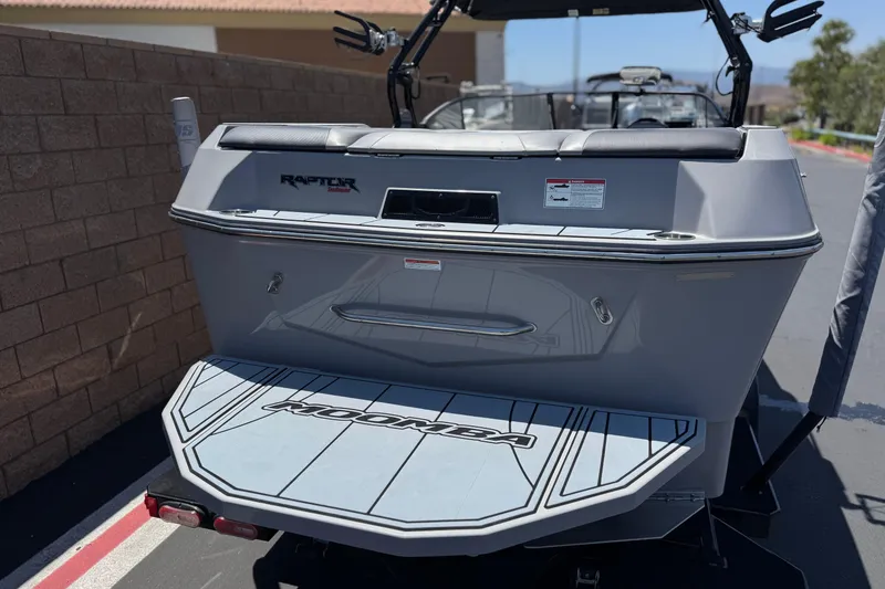 Slide: The Image of 2022 Moomba Max boat rear view with Raptor engine branding, parked outdoors. - 6