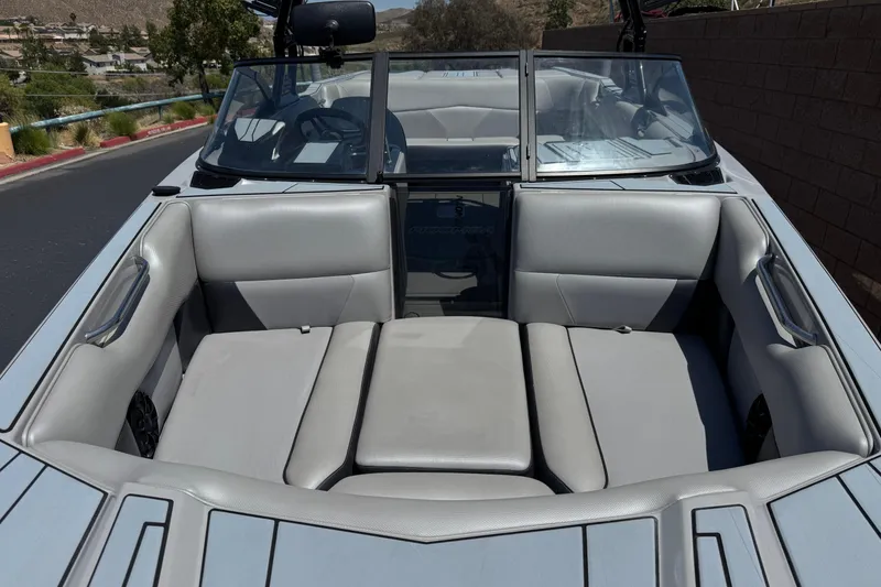 Slide: The Image of 2022 Moomba Max boat interior with gray seating and windshield, parked outdoors. - 9