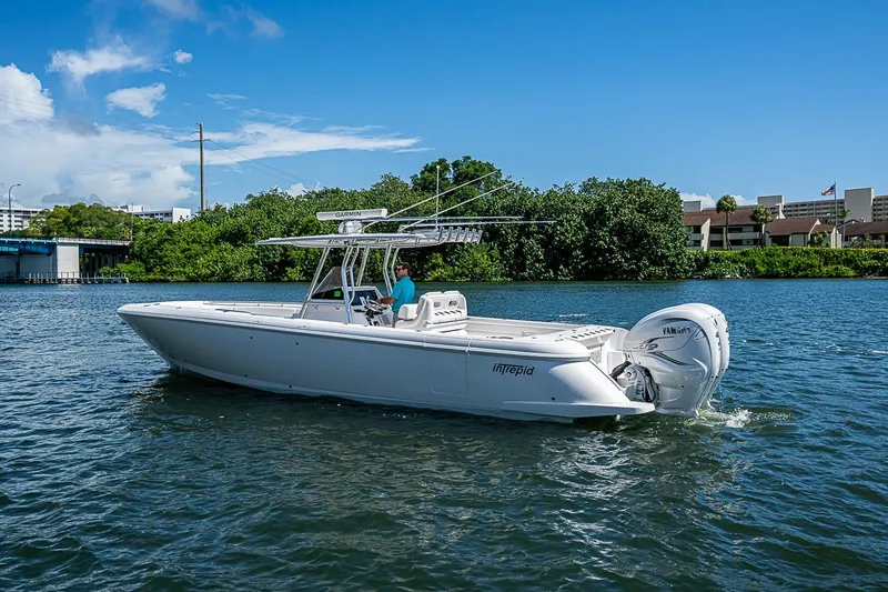 Slide: The Image of 2020 Intrepid 345 Nomad FE boat cruising on a sunny day near lush greenery. - 10