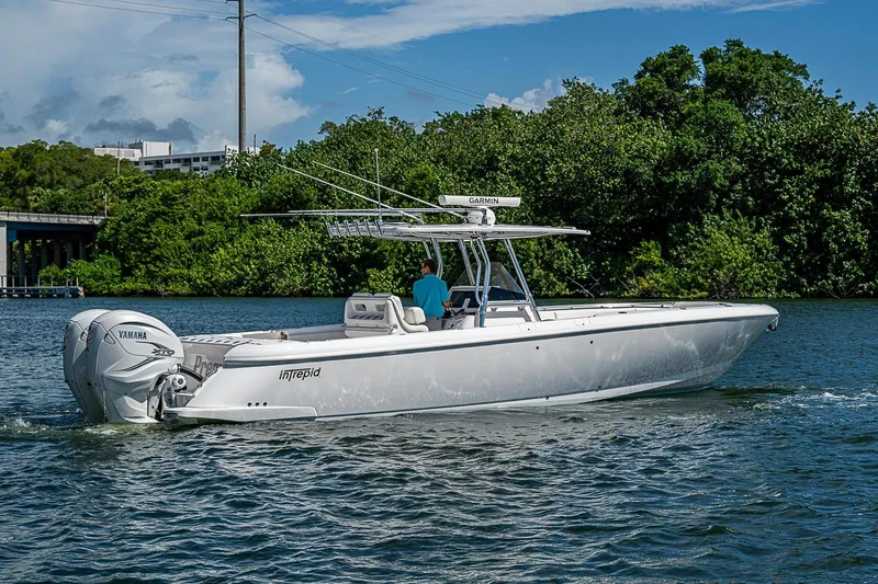 Slide: The Image of 2020 Intrepid 345 Nomad FE boat cruising on a scenic waterway with lush greenery. - 14