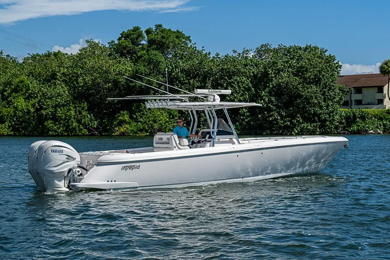 Slide: The Image of 2020 Intrepid 345 Nomad FE boat cruising on a sunny day with lush greenery background. - 15