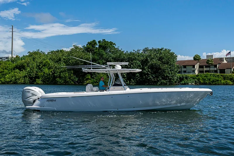 Slide: The Image of 2020 Intrepid 345 Nomad FE boat cruising on a sunny day near lush greenery. - 16
