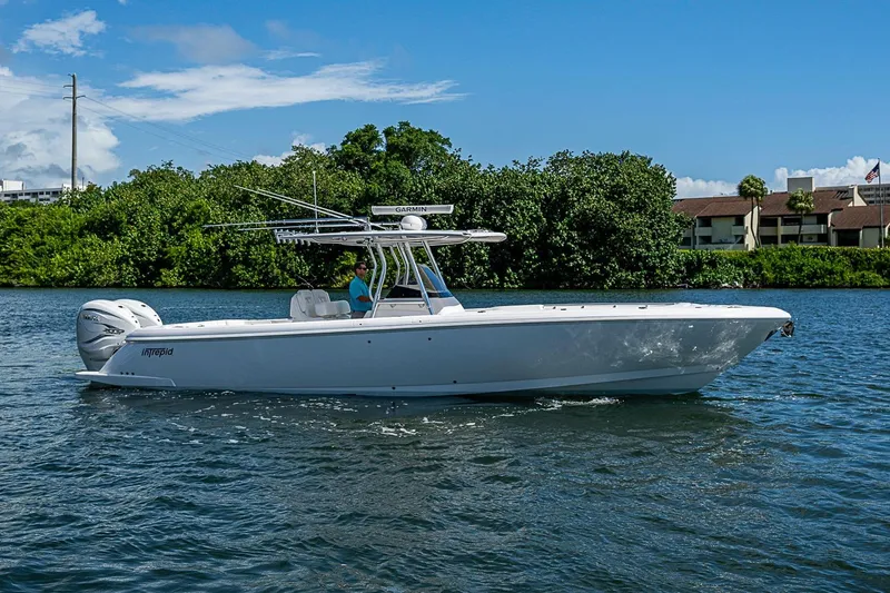 Slide: The Image of 2020 Intrepid 345 Nomad FE boat cruising on a sunny day near lush greenery. - 17