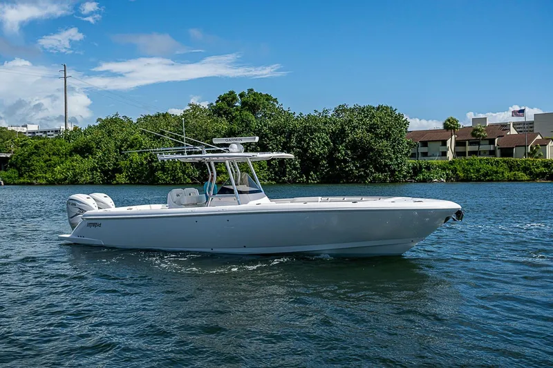 Slide: The Image of 2020 Intrepid 345 Nomad FE boat cruising on a sunny day near lush greenery. - 18