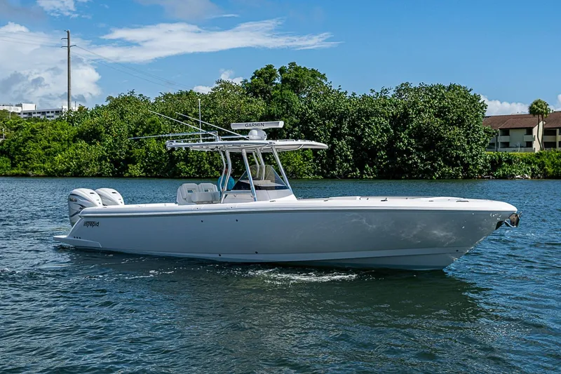 Slide: The Image of 2020 Intrepid 345 Nomad FE boat cruising on a sunny day, surrounded by lush greenery. - 19