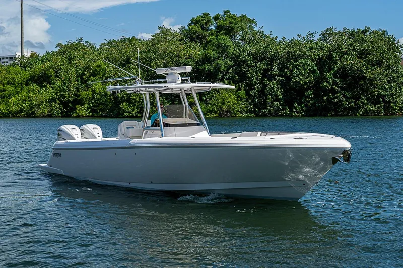 Slide: The Image of 2020 Intrepid 345 Nomad FE boat cruising on a calm river with lush greenery. - 20